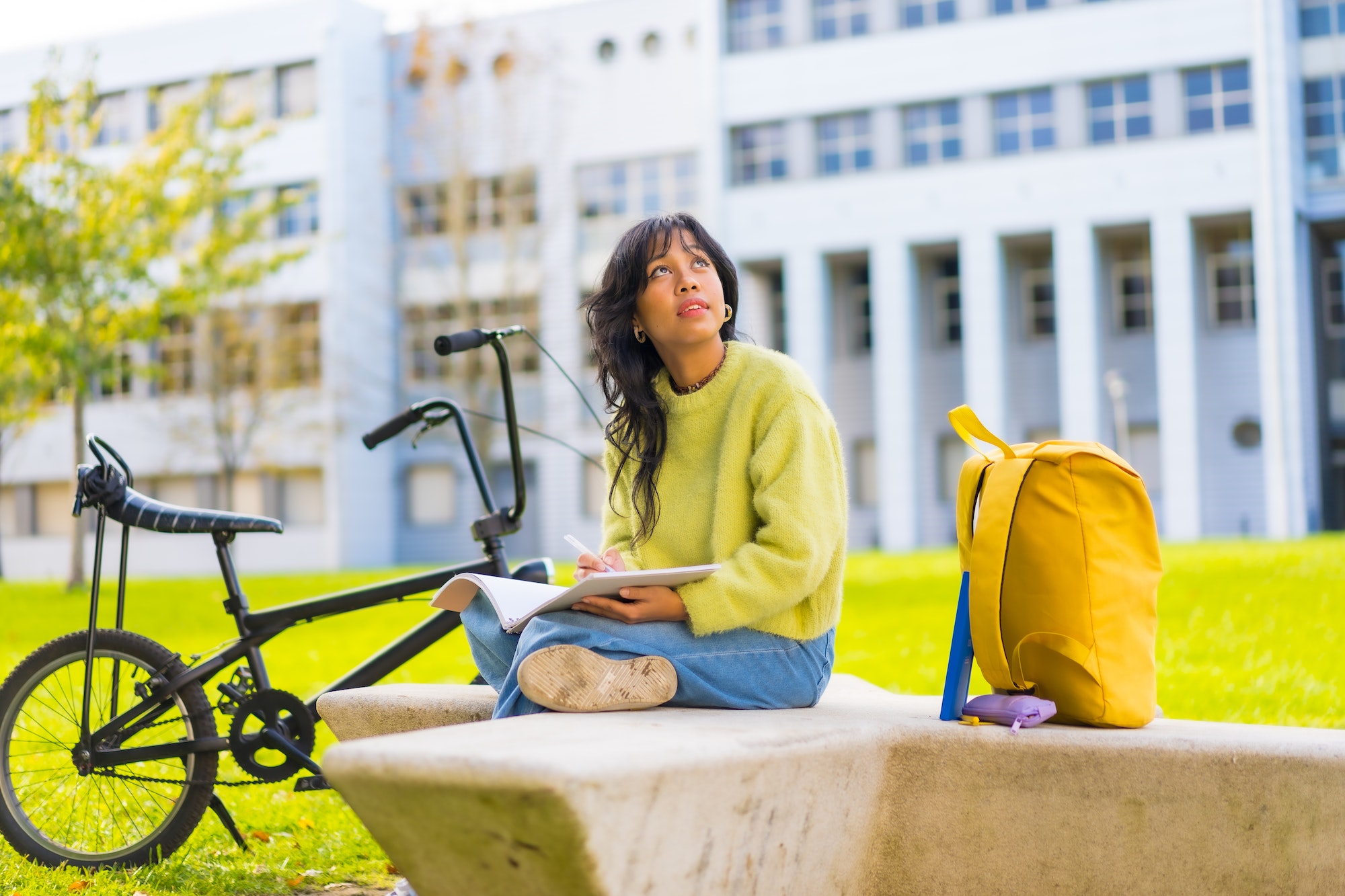 Asian art student sitting in college campus making a drawing in a notebook